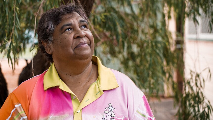 一位土著妇女穿着黄色领子的粉色衬衫的短发